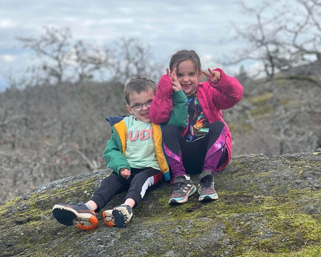 two kids sitting on rock with moss